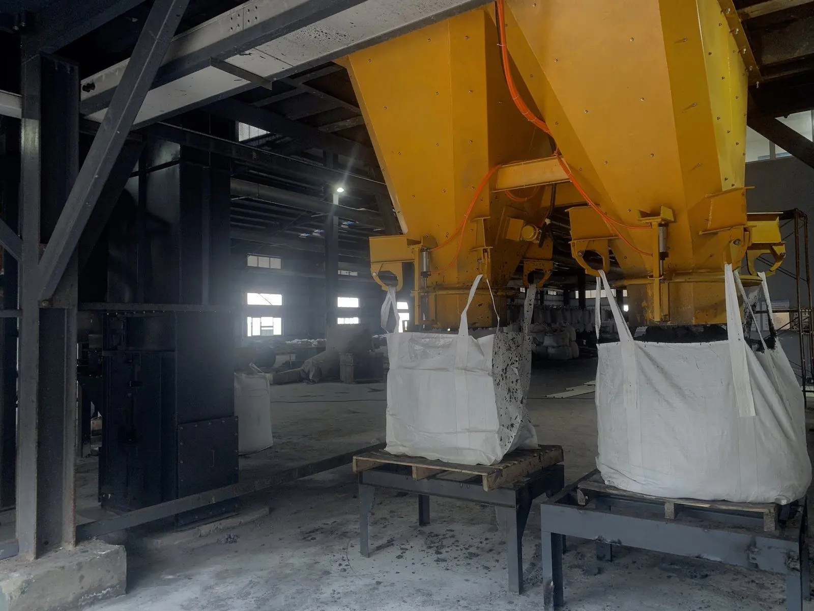 Treated material discharged from a twin-shaft mixer into bulk bags