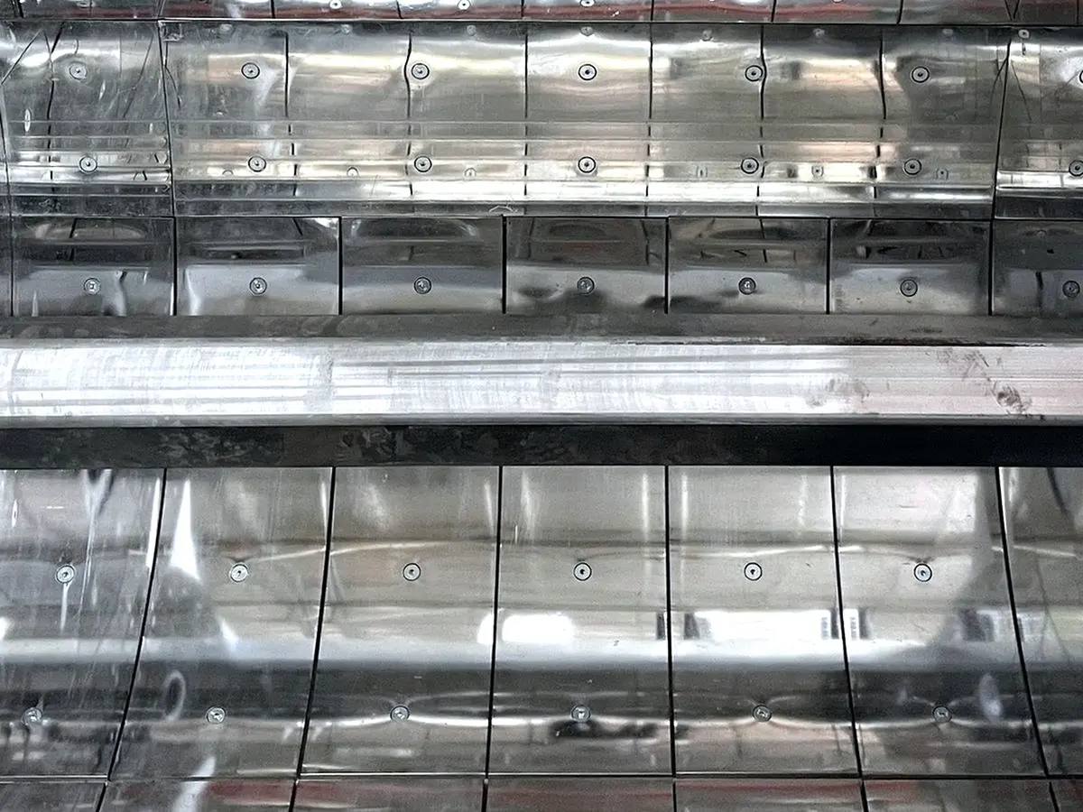 Mixer trough lined with bolted stainless steel plates