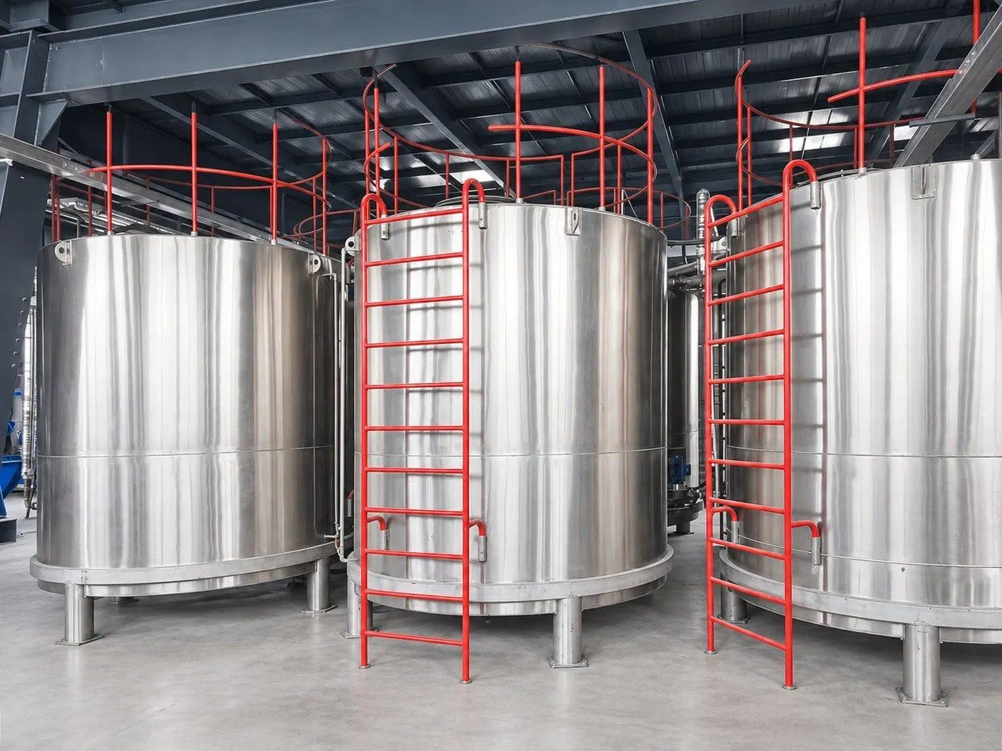 Three stainless steel reagent tanks with red access ladders