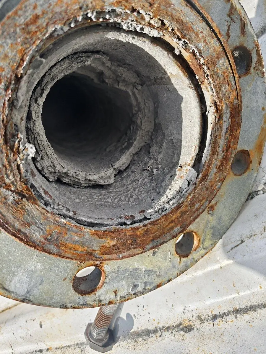 Right-angle discharge pipe opened up, bore caked with ash, before the retrofit