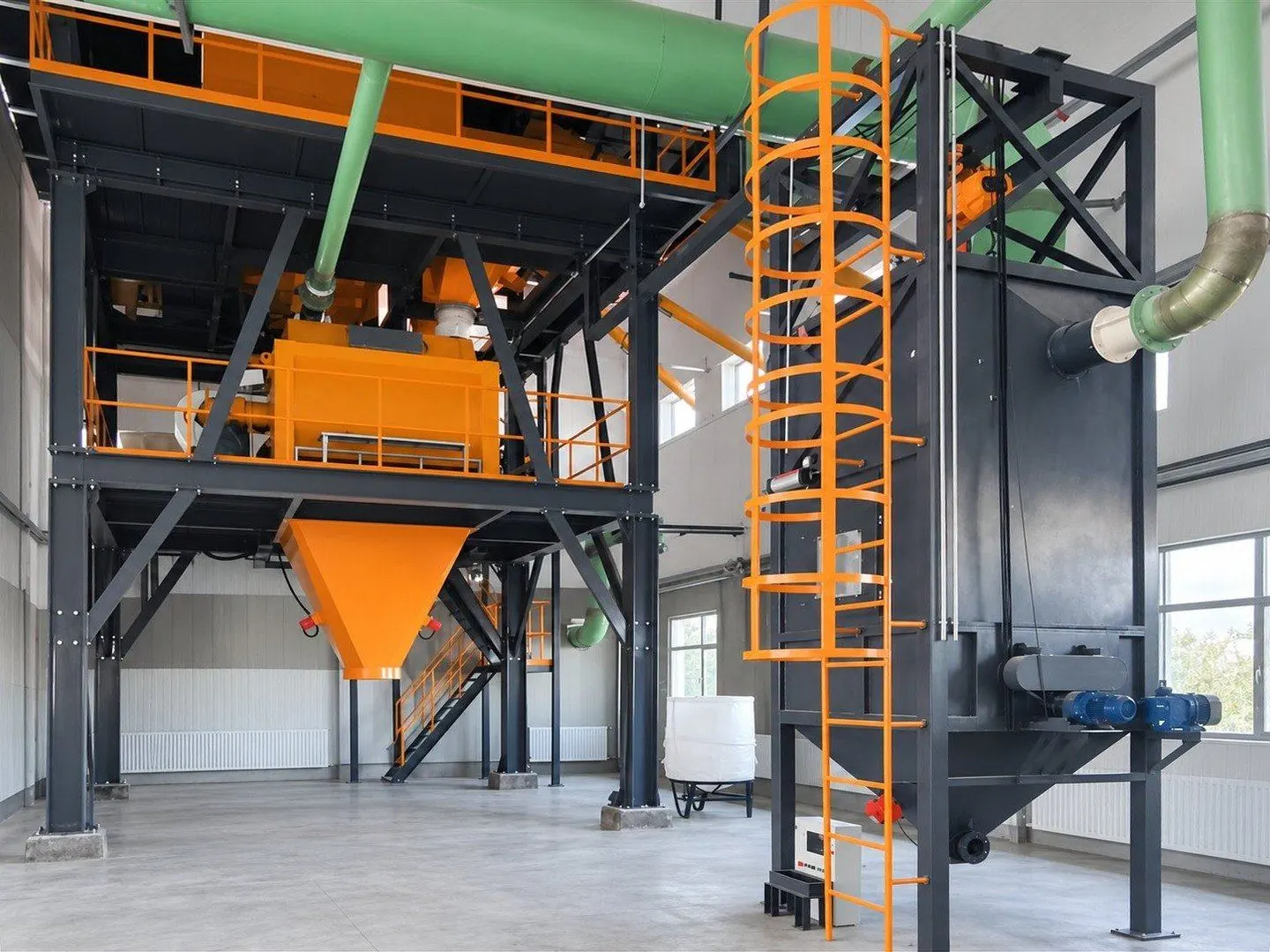 Mixing platform with an orange mixer and discharge cone, beside a tall bag unloading station with a caged ladder