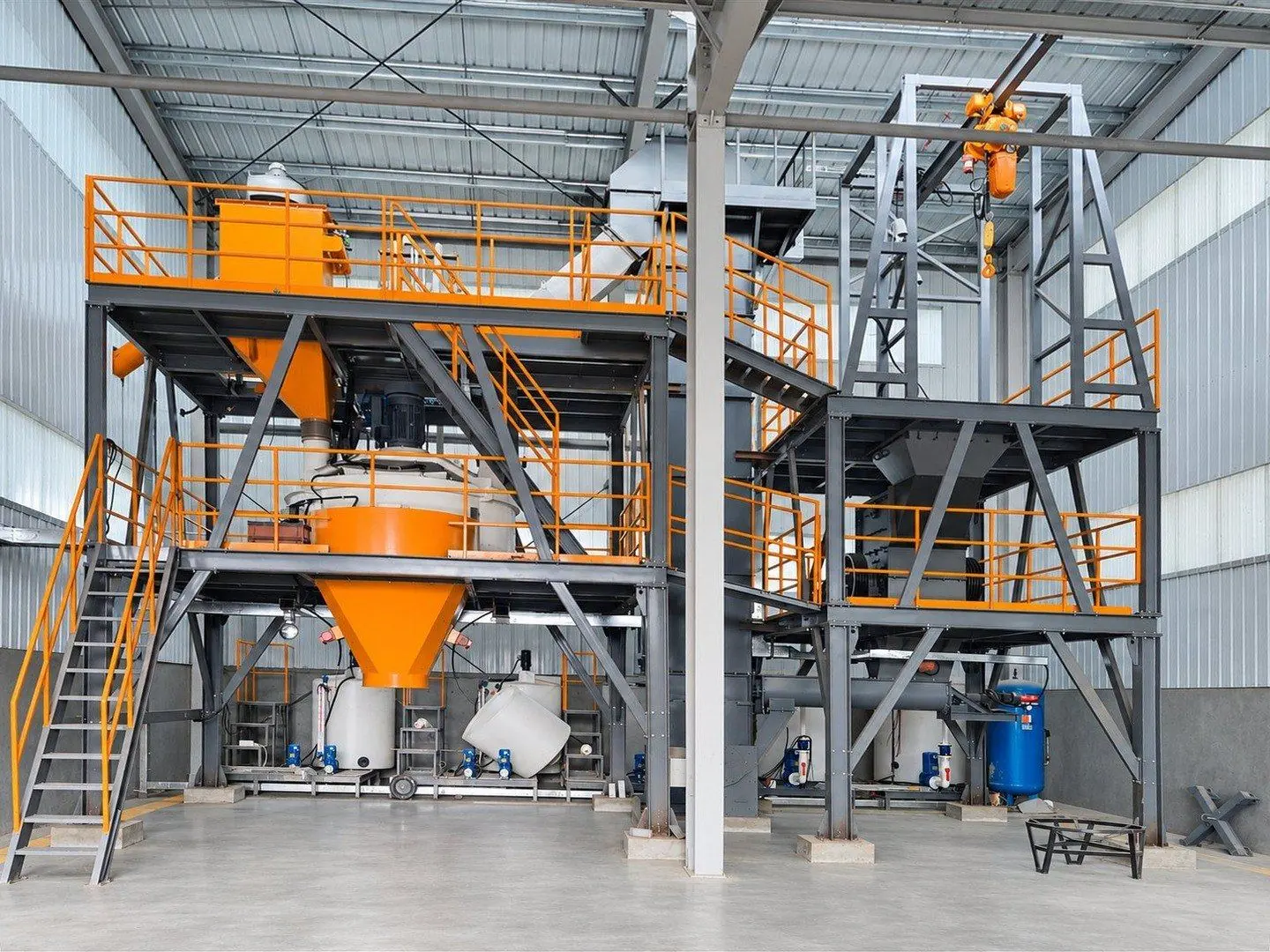 Two-level stabilization line with orange hoppers, a bag lifting tower with hoist and reagent tanks underneath