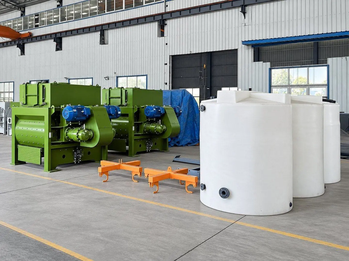 Two finished green twin-shaft mixers with blue motors, orange bag lifting frames and white reagent tanks